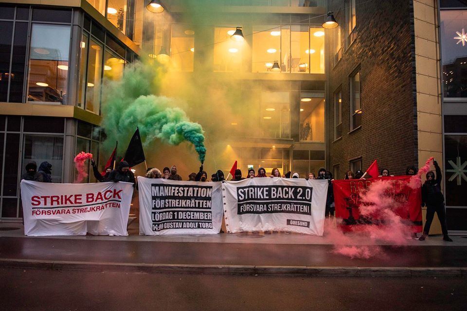 Workers with colored smoke tubes and signs in Swedish and English.